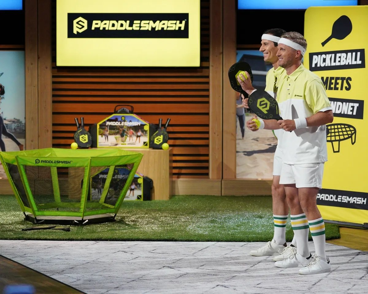 PaddleSmash Shark Tank Episode 4 Update & Net Worth PaddleSmash, a new and innovative outdoor game that combines elements of Pickleball and Spikeball, made an exciting appearance on Shark Tank during Season 15, Episode 4, which aired on October 20, 2023. The game, which comes with a net system, a foldable court, paddles, and two balls, is designed for 2 to 4 players. Each match lasts about 15 minutes, providing fast-paced, competitive fun for players of all ages. During their pitch, founders Tim Swindle and Scott Brown sought $250,000 for 10% equity in their company. After some intense negotiations, they secured a deal with Sharks Mark Cuban and Robert Herjavec for $250,000 for 20% equity. Since their appearance on the show, PaddleSmash has seen a significant increase in interest and sales, contributing to its growing success. As of April 2024, PaddleSmash has an estimated net worth of $1.2 million. What is PaddleSmash? How Does it Work? PaddleSmash is a new outdoor game that ingeniously combines the best elements of two popular sports: Pickleball and Spikeball. The game includes a net system, a foldable court, paddles, and two balls, allowing for versatile play setups. It’s designed for 2 to 4 players and can be played in small spaces, making it perfect for backyards, parks, and other recreational areas. The rules of PaddleSmash are straightforward. Players use the paddles to hit the ball over the net, similar to Pickleball, but with the added twist of bouncing the ball off the net, as in Spikeball. Each match is fast-paced, lasting about 15 minutes, making it ideal for those looking for a quick and engaging game. The game’s portability and ease of setup have contributed to its popularity, especially among families and groups looking for a fun, new outdoor activity. PaddleSmash Shark Tank Episode 4 Season 15: What Happened at Shark Tank Pitch? During their appearance on Shark Tank Season 15, Episode 4, founders Tim Swindle and Scott Brown introduced PaddleSmash to the Sharks. They asked for $250,000 in exchange for 10% equity, valuing their company at $2.5 million. The founders explained that PaddleSmash was a new and exciting outdoor game that had already gained traction in the market. The landed cost of the product was $55, and it was being sold for $199.99. The founders revealed that the company had been in business for just 9 months but had already achieved $700,000 in sales. They also mentioned a royalty agreement with Joe Bingham, the inventor of the game, who receives a 5% royalty on net sales. The Sharks were impressed with the product's potential, but the conversation quickly turned to the company’s valuation. Kevin O’Leary initially offered $250,000 for 20% equity at a $1.2 million valuation. However, Mark Cuban and Robert Herjavec teamed up to offer the same amount for the same equity stake. After some back-and-forth, the founders accepted the offer from Cuban and Herjavec, securing the investment they needed to grow their business. PaddleSmash Shark Tank Pitch Summary Company Name PaddleSmash Founder Tim Swindle, Scott Brown, Joe Bingham Product New Outdoor Game Amount Asked For $250,000 for 10% equity Final Deal $250,000 for 20% equity Investor Mark Cuban, Robert Herjavec Season & Episode (USA) Season 15, Episode 4 Lifetime Sales $1 million estimated Business Status In Business Current Net Worth $1.2 million estimated What Happened to PaddleSmash After Shark Tank? After securing a deal with Mark Cuban and Robert Herjavec on Shark Tank, PaddleSmash experienced a surge in sales and interest. The exposure from the show significantly boosted the company’s visibility, leading to increased orders from customers eager to try out the new game. The company also benefited from the expertise and resources of its new investors, which helped in refining their marketing strategy and expanding their reach. The investment allowed PaddleSmash to scale its operations, particularly in terms of inventory and social media marketing. The game is now available on major retail platforms, including Amazon, Dicks Sporting Goods, Scheels, and Academy Sports + Outdoors, as well as on the company’s official website. This expansion has solidified PaddleSmash's position in the competitive outdoor games market. How Much Is PaddleSmash Worth? As of 2024, PaddleSmash is estimated to be worth $1.2 million. This valuation reflects the company’s rapid growth since its launch in 2022 and its success in securing a deal on Shark Tank. The game’s strong profit margins, combined with the growing popularity of outdoor recreational activities, have positioned PaddleSmash as a promising player in the industry. Is PaddleSmash Still in Business? Yes, PaddleSmash is still in business and continues to thrive. The company has maintained its momentum following its Shark Tank appearance, expanding its customer base and solidifying its market presence. With the backing of Mark Cuban and Robert Herjavec, PaddleSmash is well-positioned to continue its growth and introduce even more people to this exciting new game. Which Episode & Season Number Was PaddleSmash on Shark Tank? PaddleSmash was featured on Shark Tank during Season 15, Episode 4, which aired on October 20, 2023. In this episode, the founders, Tim Swindle and Scott Brown, successfully secured a deal with Mark Cuban and Robert Herjavec for $250,000 in exchange for 20% equity in their company. ________________________________________ Frequently Asked Questions Who are the founders of PaddleSmash? PaddleSmash was founded by Tim Swindle, Scott Brown, and Joe Bingham. Joe Bingham is the inventor of the game. What is PaddleSmash? PaddleSmash is a new outdoor game that combines elements of Pickleball and Spikeball, designed for 2 to 4 players. It includes a net system, a foldable court, paddles, and two balls. Did PaddleSmash get a deal on Shark Tank? Yes, PaddleSmash secured a deal with Mark Cuban and Robert Herjavec for $250,000 for 20% equity. How much is PaddleSmash worth? As of 2024, PaddleSmash is estimated to be worth $1.2 million. Is PaddleSmash still in business? Yes, PaddleSmash is still in business and continues to grow. Which episode of Shark Tank featured PaddleSmash? PaddleSmash was featured on Shark Tank Season 15, Episode 4.